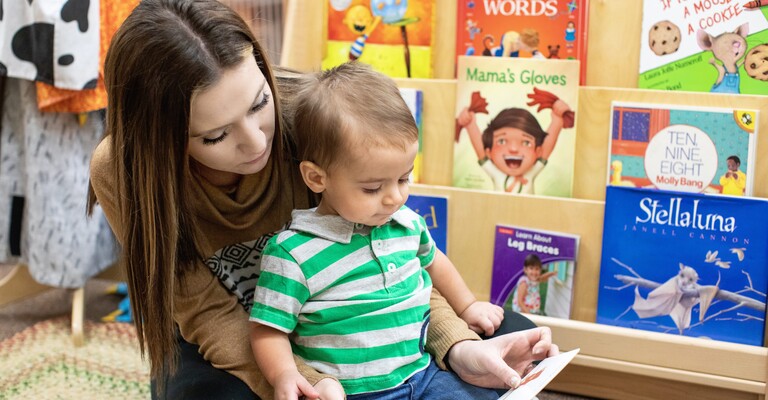 early childhood student reading a book to toddler in lap