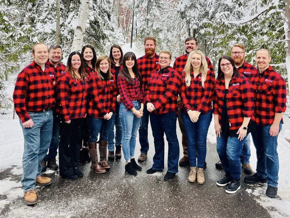 group photo of staff members in flannel shirts outside in winter