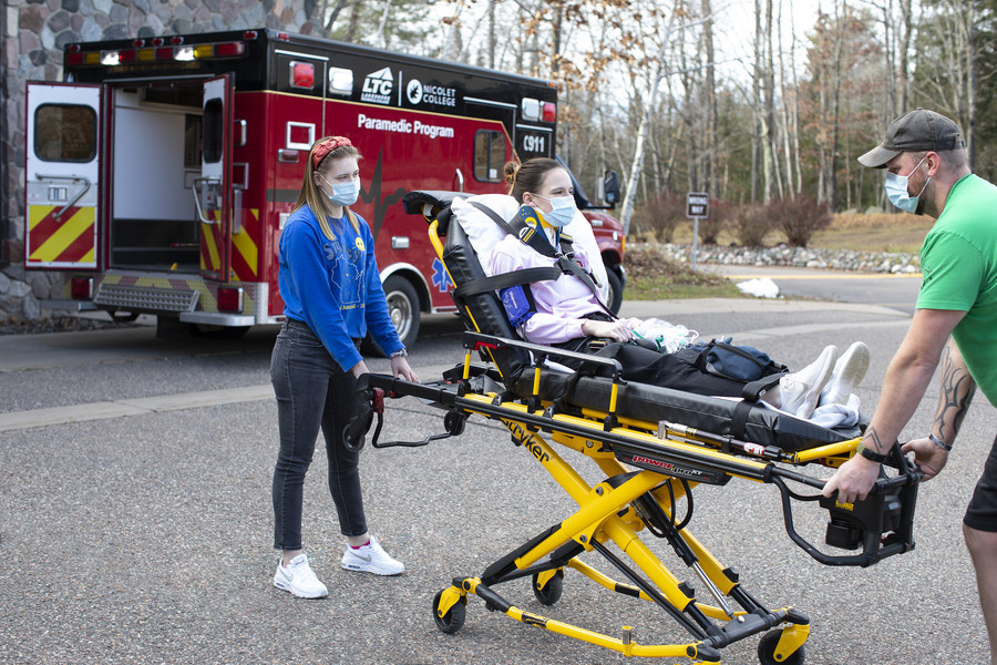 students training to be EMT by pushing stretcher to ambulance