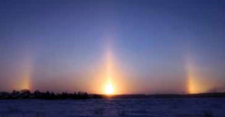 sun setting over field of snow