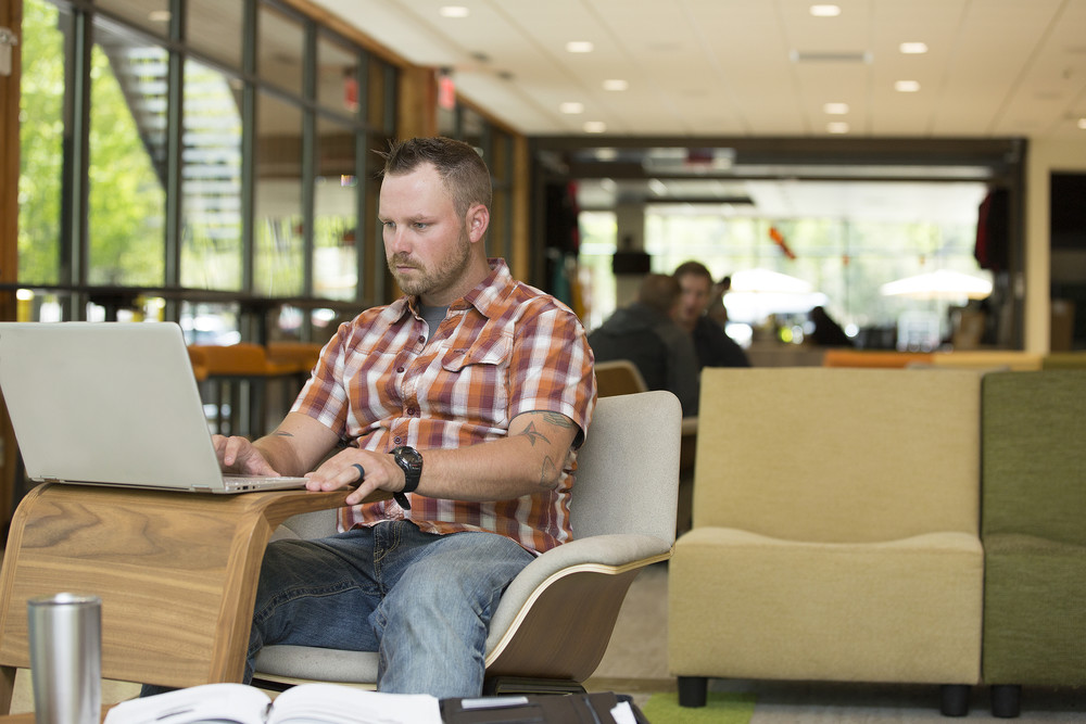 adult student in lounge with laptop