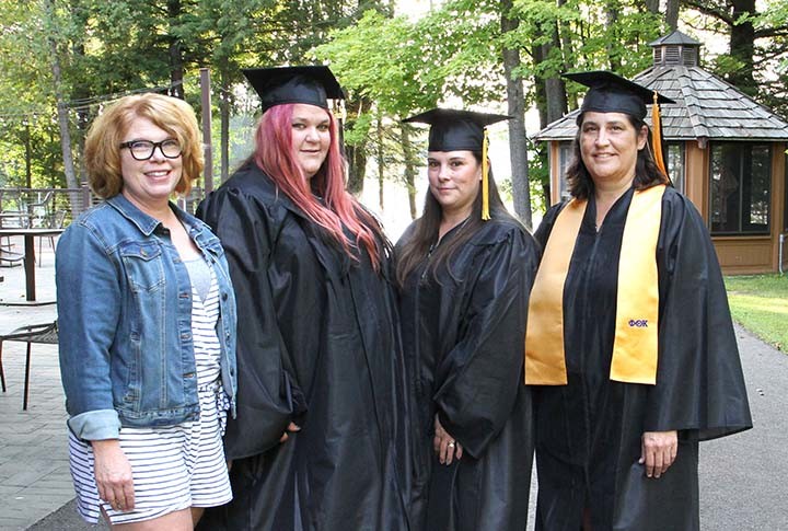 three female graduates and one female instructor outside smiling for photo