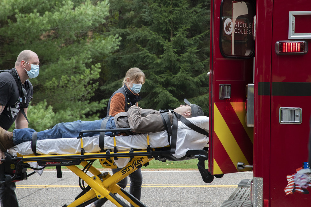 male emt loading a male patient on stretcher into ambulance as female emt looks on