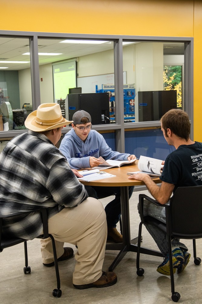 three male students studying at a table together