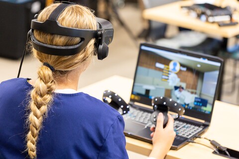 Virtual Reality nursing student working on computer with VR headset