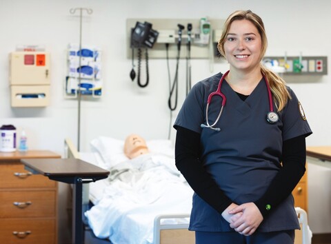 A smiling nursing student in a classroom.