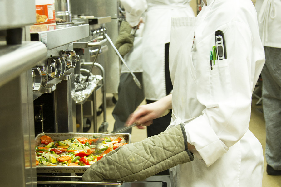 culinary student roasting vegetables in pan