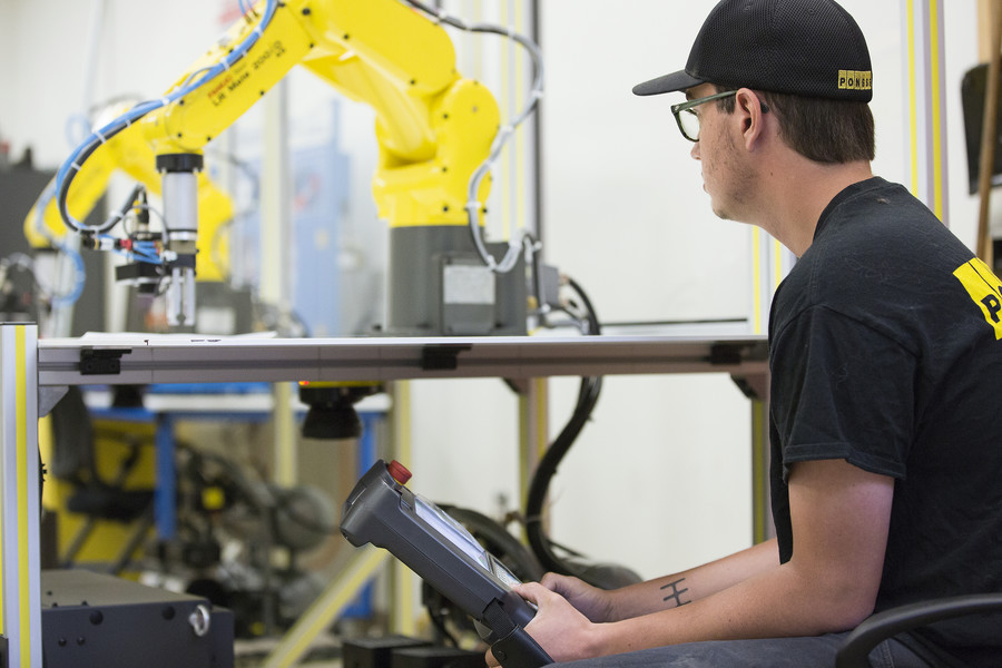 Electromechanical student operating robotic arm